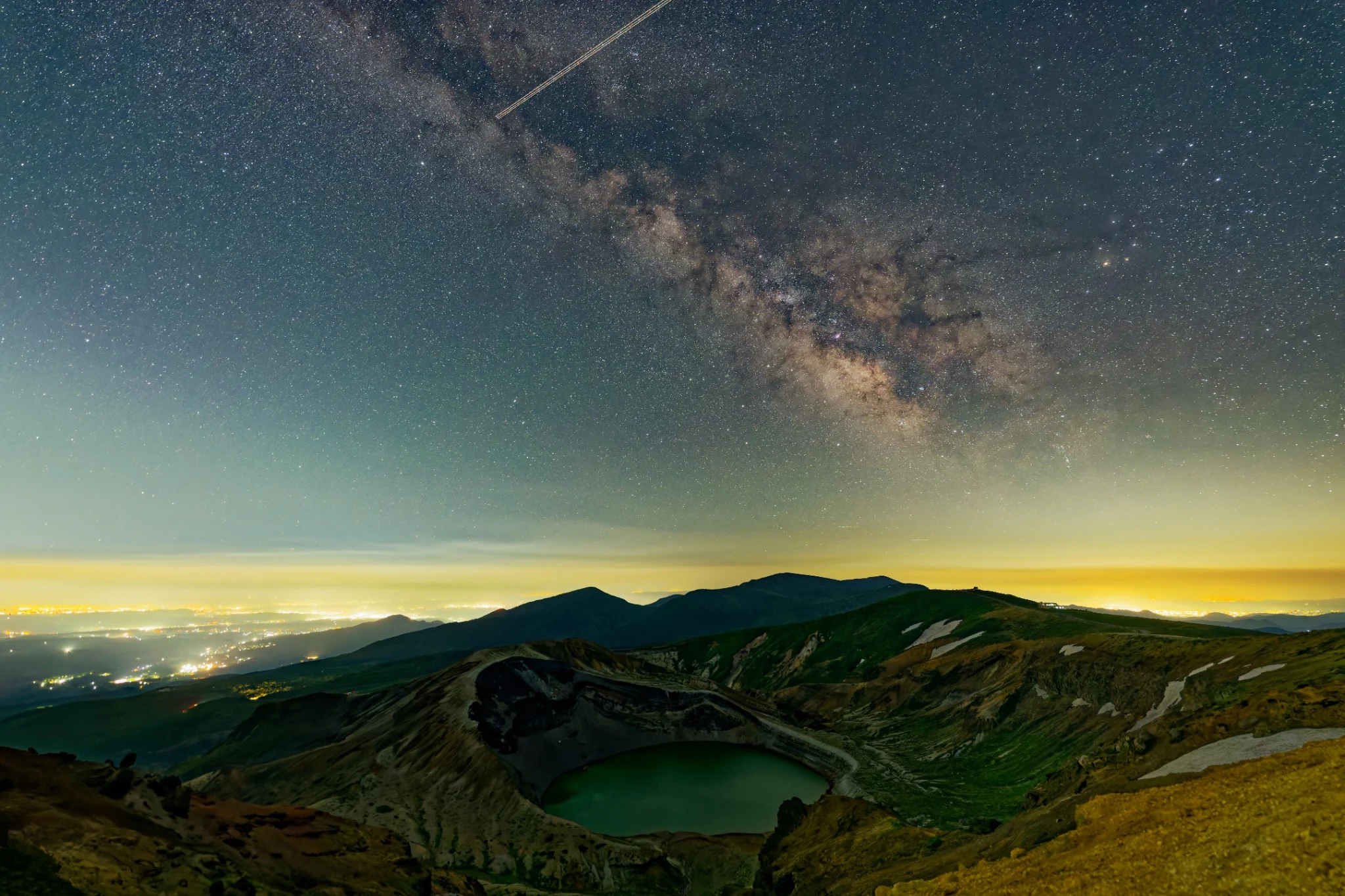 The Milky Way arching over Okama crater lake and the surrounding mountains