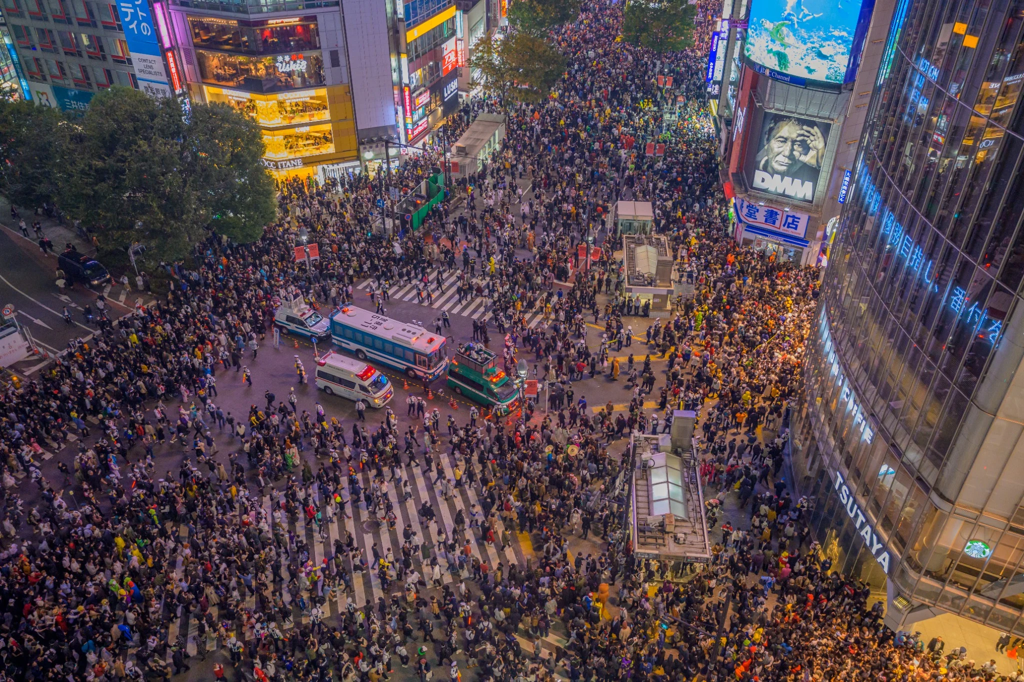 Crowds crossing Shibuya surrounded by illuminated signs